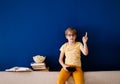 Blonde schoolboy boy plays video games, holds a gamepad, eats popcorn instead of learning lessons on blue background Royalty Free Stock Photo