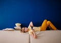 Blonde schoolboy boy plays video games, holds a gamepad, eats popcorn instead of learning lessons on blue background