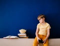 Blonde schoolboy boy plays video games, holds a gamepad, eats popcorn instead of learning lessons on blue background Royalty Free Stock Photo