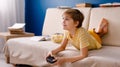 Blonde schoolboy boy plays video games, holds a gamepad, eats popcorn instead of learning lessons on blue background Royalty Free Stock Photo