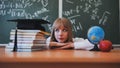 Blonde schoolgirl with bangs poses in front of school objects.