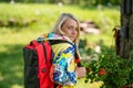 blonde middle-aged woman in bright clothes with a backpack in the park on a sunny day, rear view Royalty Free Stock Photo