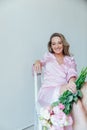 blonde sits with flowers on a white background in a bright room Royalty Free Stock Photo