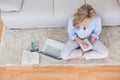 Blonde sitting on carpet taking notes Royalty Free Stock Photo