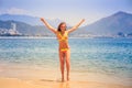 Blonde slim girl in bikini poses on tip toe on beach Royalty Free Stock Photo