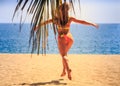 blonde slim gymnast in bikini backside view jumps over sand Royalty Free Stock Photo