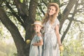 blonde smiling mother and daughter in straw hats holding appples