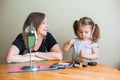 Blonde smiling mother with her preschooler daughter playing with make up accessories and mirror Royalty Free Stock Photo