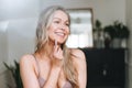 Blonde smiling woman 35 year plus clean fresh face and hands with long hair does facial massage with gouache scraper in underwear Royalty Free Stock Photo