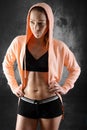 Blonde sporty athletic young woman wearing open hoodie in studio