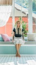 Blonde in a straw hat sits on the couch by the window. the image of a modern girl. Model with tattoos Royalty Free Stock Photo