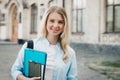 Student girl is smiling and holding a folder and a notebook in her hands on a university background. Girl is taking exams Royalty Free Stock Photo