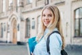 Student girl is smiling and holding a folder and a notebook in her hands on a university background. Girl is taking exams Royalty Free Stock Photo