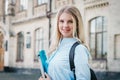 Student girl is smiling and holding a folder and a notebook in her hands on a university background. Girl is taking exams Royalty Free Stock Photo