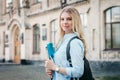 Student girl is smiling and holding a folder and a notebook in her hands on a university background. Girl is taking exams Royalty Free Stock Photo