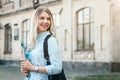 Student girl is smiling and holding a folder and a notebook in her hands at university background. Girl is taking exams Royalty Free Stock Photo