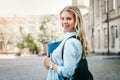 Student girl is smiling and holding a folder and a notebook in her hands at university background. Girl is taking exams Royalty Free Stock Photo