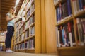 Blonde student reading book next to bookshelf Royalty Free Stock Photo