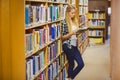 Blonde student reading book next to bookshelf Royalty Free Stock Photo