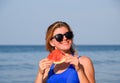 A blonde in sunglasses eats a watermelon by the sea. A juicy watermelon in the hands of a woman Royalty Free Stock Photo