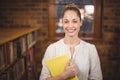 Blonde teacher holding book in the library Royalty Free Stock Photo