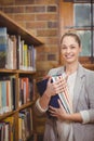 Blonde teacher holding books in the library Royalty Free Stock Photo