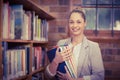 Blonde teacher holding books in the library Royalty Free Stock Photo