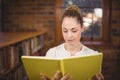 Blonde teacher reading book in the library Royalty Free Stock Photo