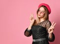 Teen girl in sunglasses, black dress and red hat. She is kissing you, showing victory hands, posing on pink background. Close up Royalty Free Stock Photo