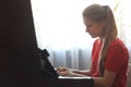 Blonde teenage girl 14-years old playing the piano at home