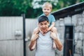 Blonde three years old boy sitting on father`s shoulders. Kazakh father and caucasian mother. Happy father with black hair play