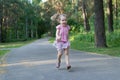 Blonde three years old girl running on asphalt park footpath