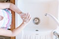 Blonde toddler girl washing hands with a soap in the lingh kitchen before eating. Hygiene and healthcare concept Royalty Free Stock Photo