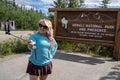 Tourist woman uses a selfie stick to take photo in front of Denali National Park sign