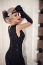 Blonde wavy hairstyle. Elegant woman portrait in retro style. Beautiful girl wears in vintage black dress and gloves. Hollywood Royalty Free Stock Photo