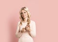 Blonde woman adult attractive beautiful smiling portrait with cellphone, mobile, cauasian and scandinavian girl on pink background Royalty Free Stock Photo