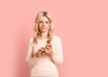 Blonde woman adult attractive beautiful smiling portrait with cellphone, mobile, cauasian and scandinavian girl on pink background Royalty Free Stock Photo