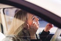 Blonde woman applying makeup in car