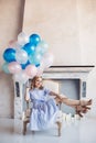 Blonde woman with balloons sit in chair