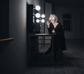 Blonde woman in black coat applying lipstick in dressing room Royalty Free Stock Photo
