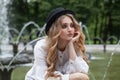 Blonde woman in black hat resting in park