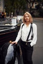 Blonde woman in black retro clothes near old vintage classic car Royalty Free Stock Photo
