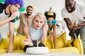 Blonde woman blowing candle on birthday cake by her