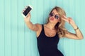 Blonde woman in bodysuit with perfect body taking selfie smartphone toned instagram filter Royalty Free Stock Photo