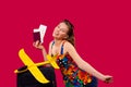 A blonde woman in bright clothes with documents, a suitcase and a bright yellow toy plane, happy to travel and posing on Royalty Free Stock Photo