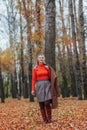 A blonde woman in bright clothes walks in the autumn park. Royalty Free Stock Photo