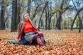 A blonde woman in bright clothes walks in the autumn park. Royalty Free Stock Photo