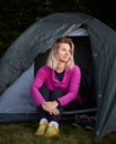 Young girl sitting in tent at summer campsite.