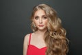 Blonde woman celebrity with makeup and long curly hairstyle in red evening dress on black background Royalty Free Stock Photo