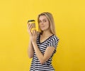 Blonde woman with coffee addict hold the disposable yellow coffee cup on a yellow background. Looking at camera
